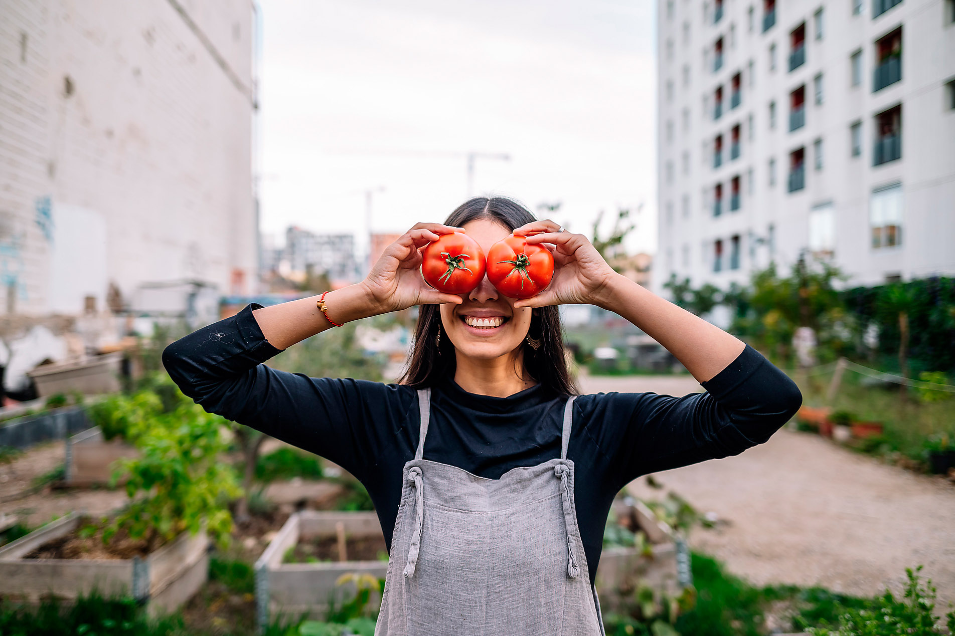 Stock photo, royalty-free, green cities, sustainability, regionality, self sufficiency, awareness, ecology, consumption, living environment, happy woman holding tomatoes over eyes in urban garden