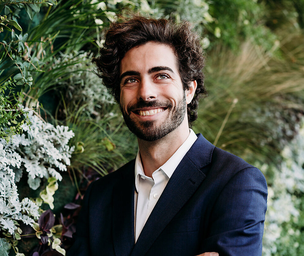 Stock photo, royalty free, happy brown haired man smiling in blue suit standing in front of wall planted with plants, future, visions, imagination, W61