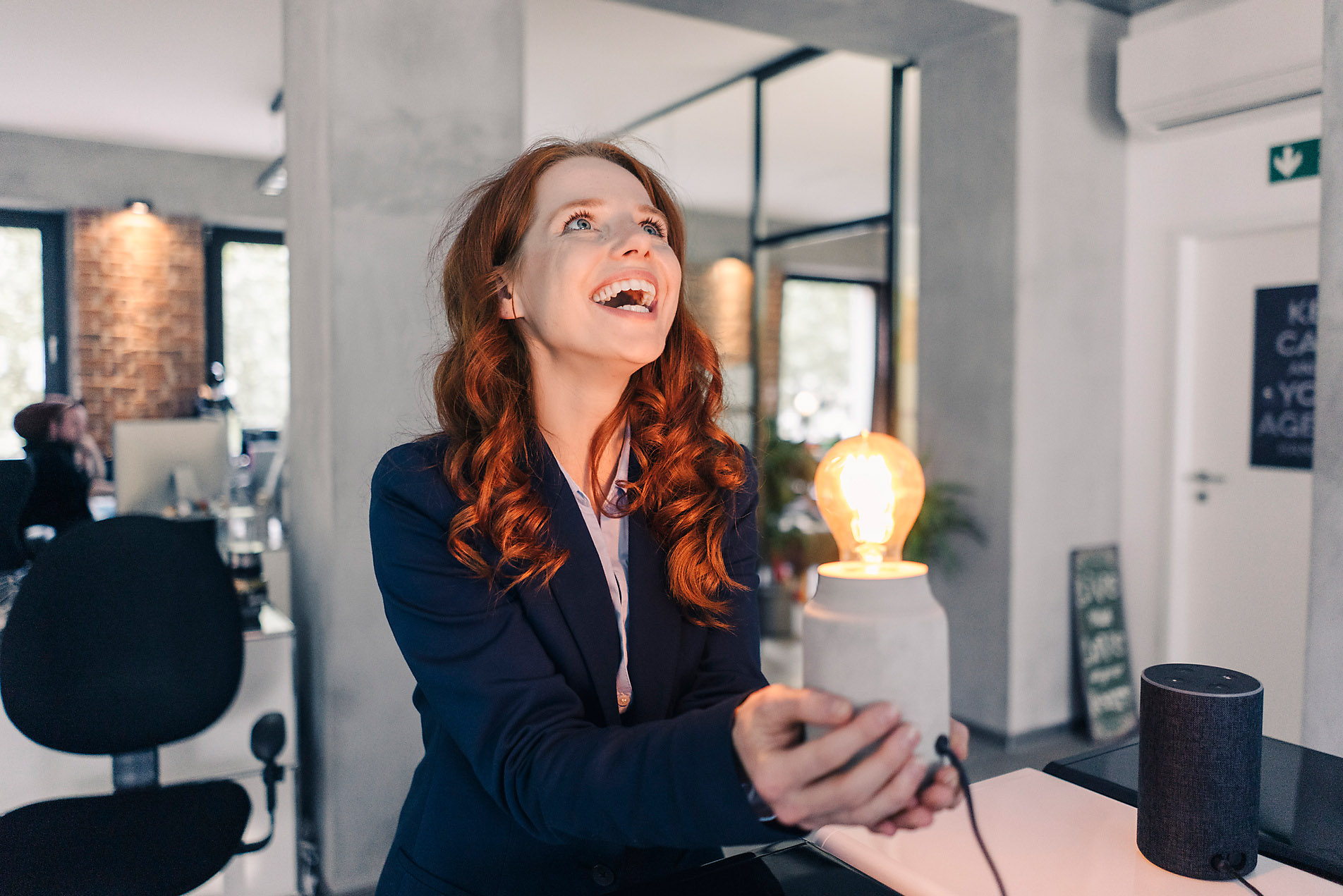 stock image, royalty-free, Laughing redheaded businesswoman holding lamp in office, future, vision, mindfulness, new work, smart, imagination