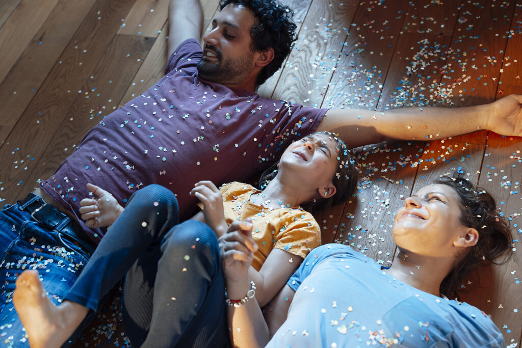 Stockfoto von glücklichen Eltern und Tochter haben Spaß mit Konfetti auf dem Boden