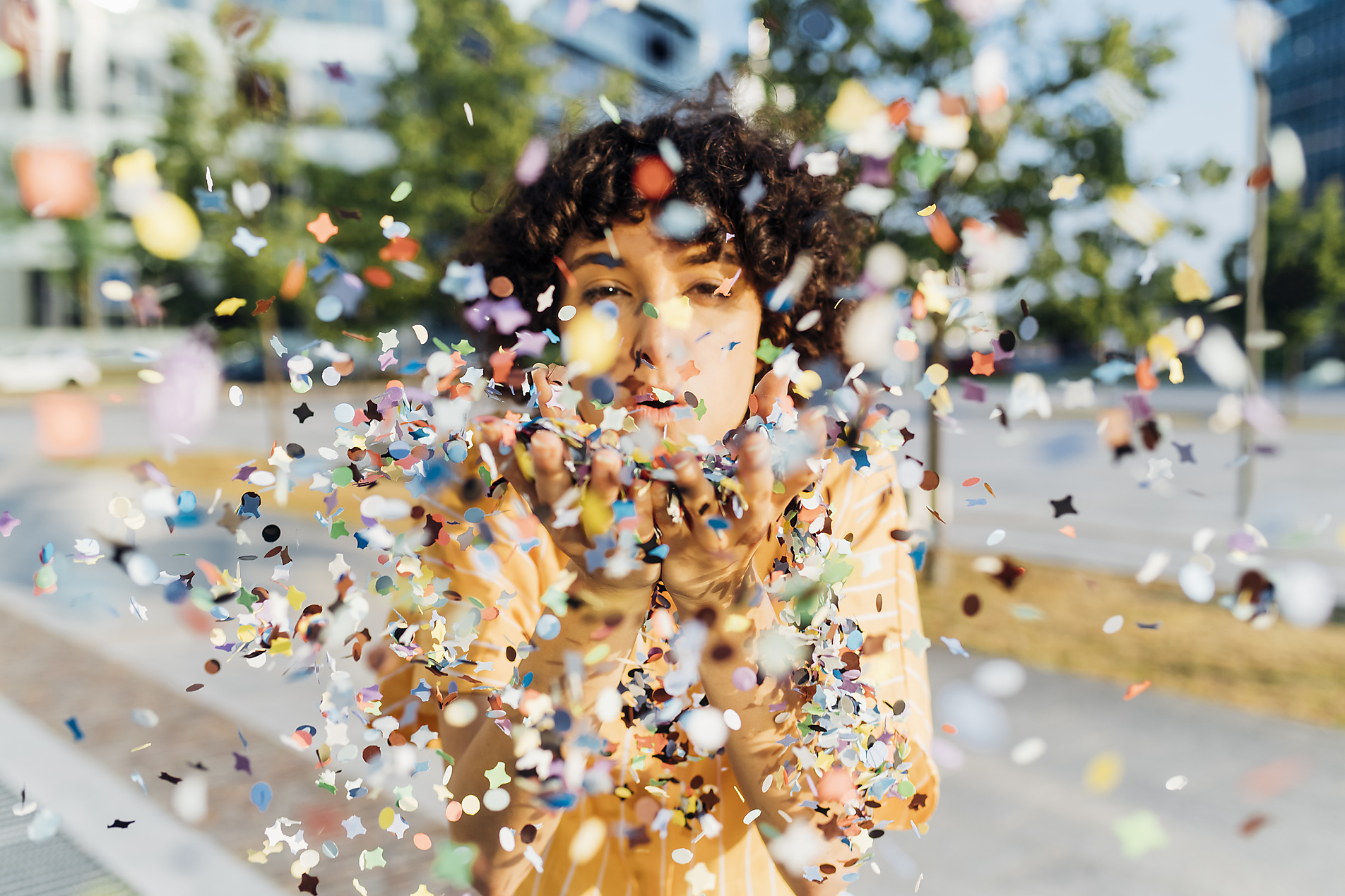 Stock Image of Young woman blowing confetti from hands