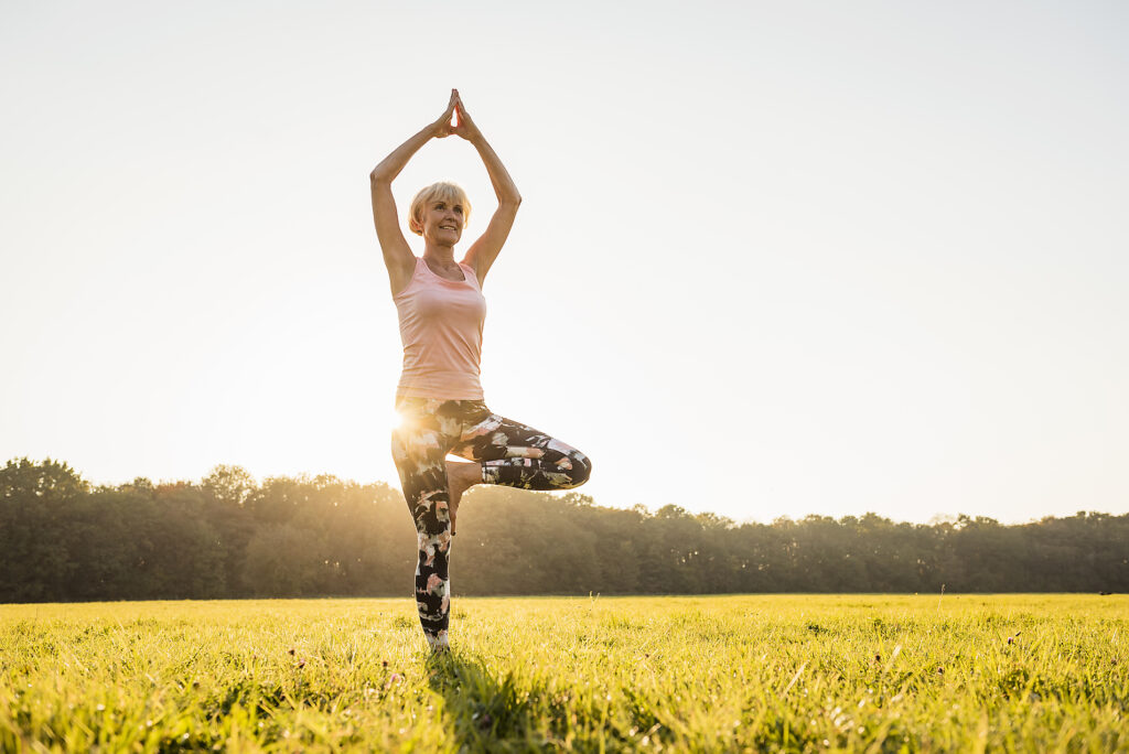 Stockfoto, Royalty Free, Senior Frau macht Yoga auf ländlichen Wiese bei Sonnenuntergang