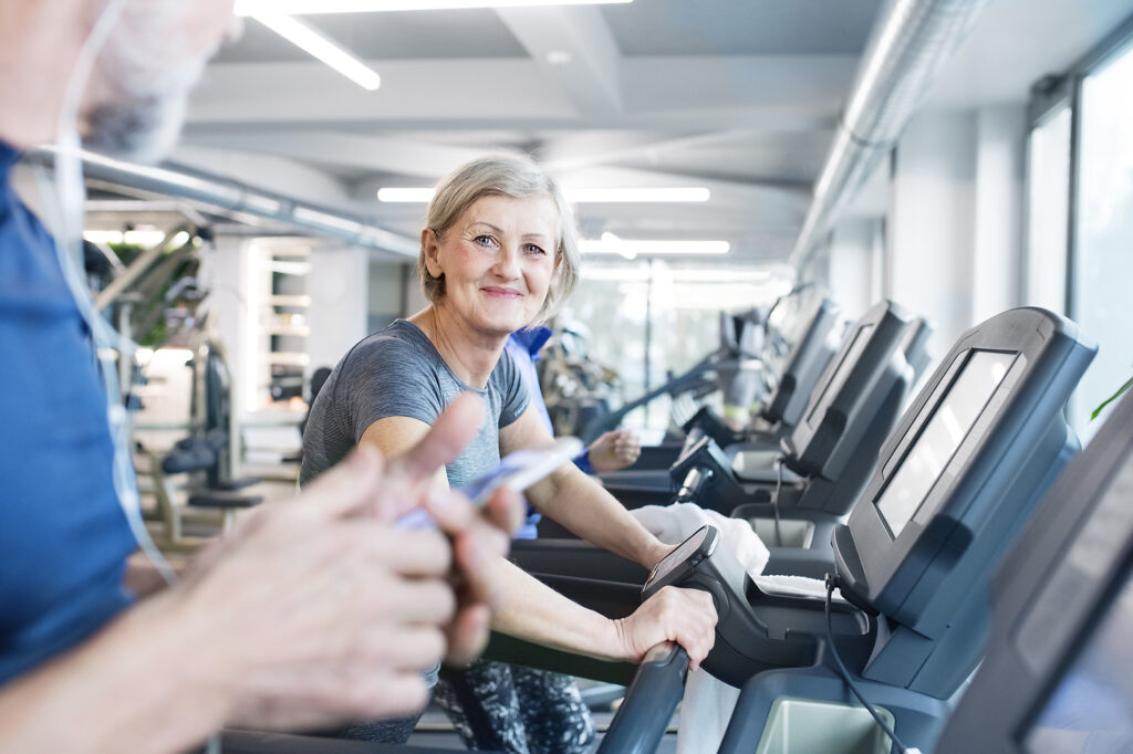 Stockfoto, Royalty Free, Gruppe fitter Senioren auf Laufbändern beim Training im Fitnessstudio, Frau lächelt