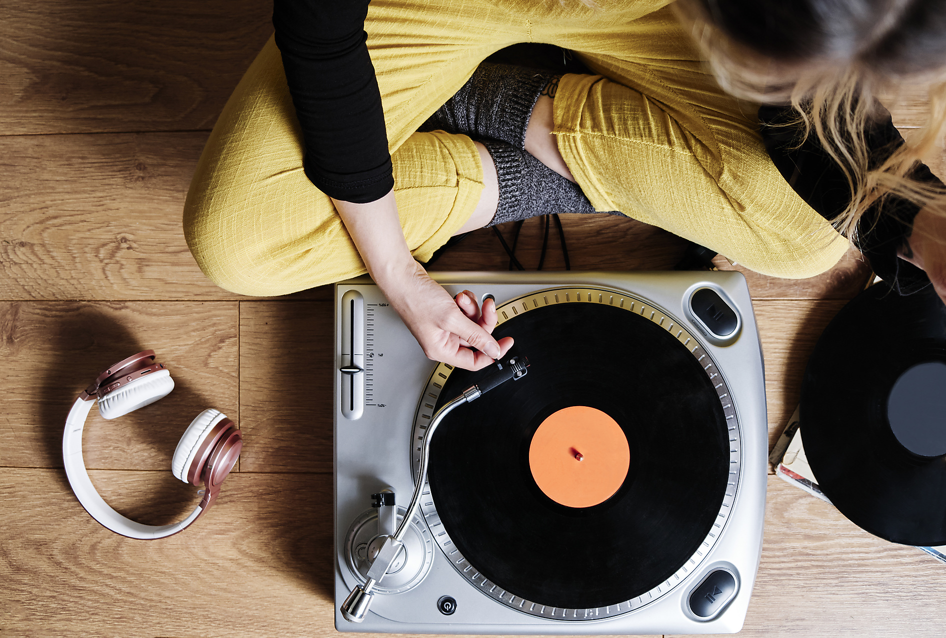 Royalty Free Stockphoto of woman adjusting tonearm of turntable while sitting on floor at home