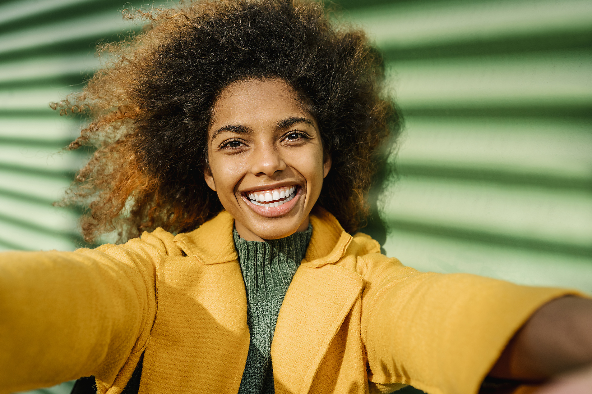 Stock Image, Royalty Free Photo, Beautiful Afro woman taking selfie against green wall
