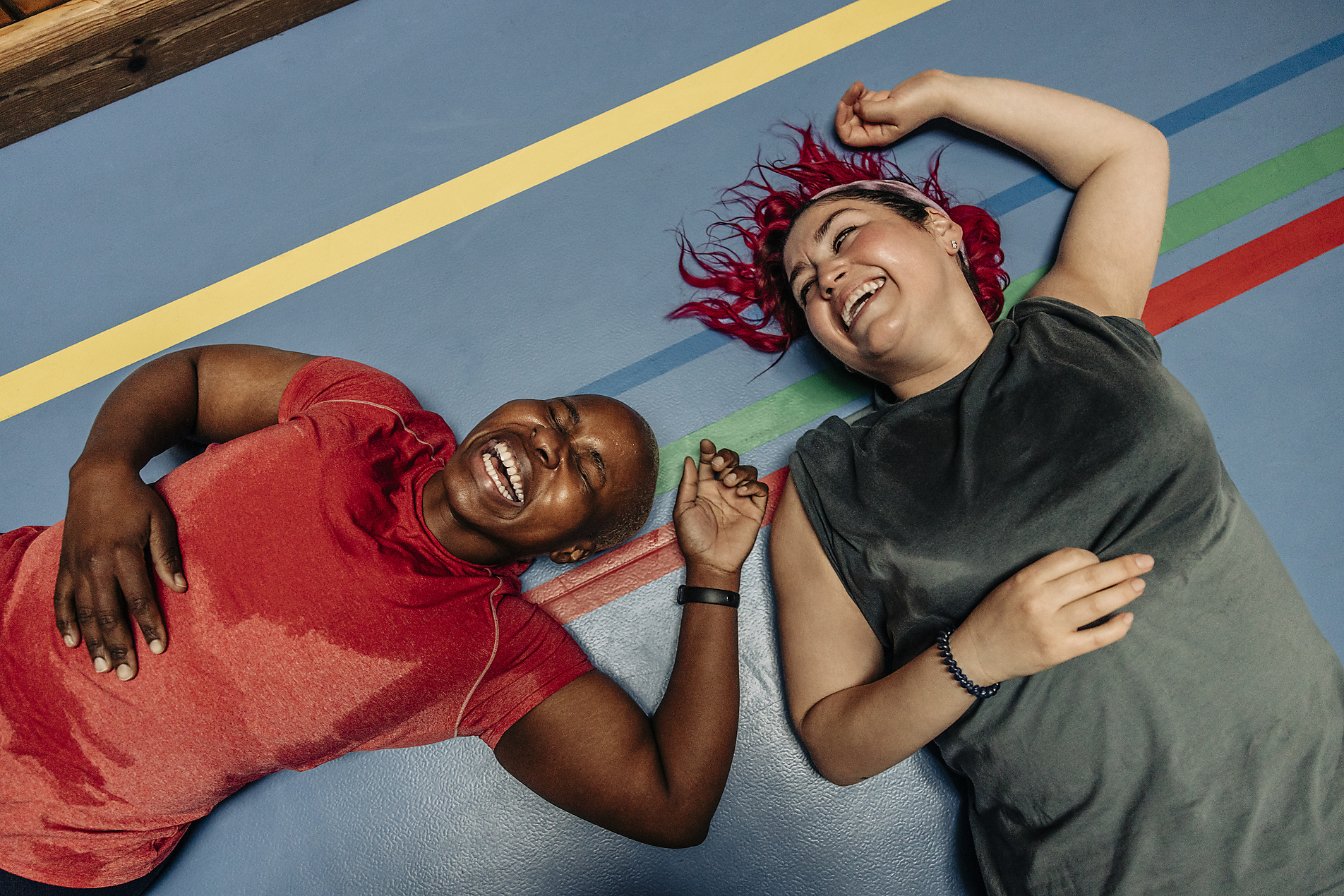 Royalty Free Stock Image of High angle view of female athletes laughing while lying on safety mat at sports court