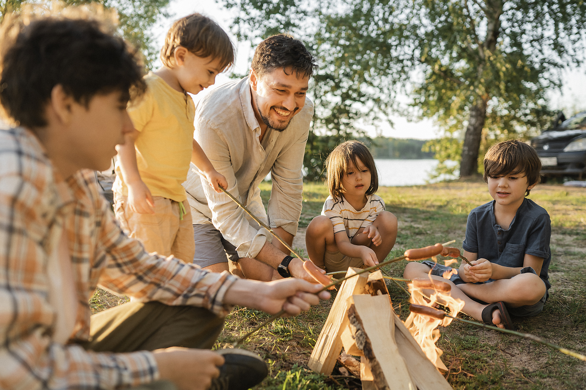 Stockimage, Royalty Free, Happy father and children roasting sausages in bonfire