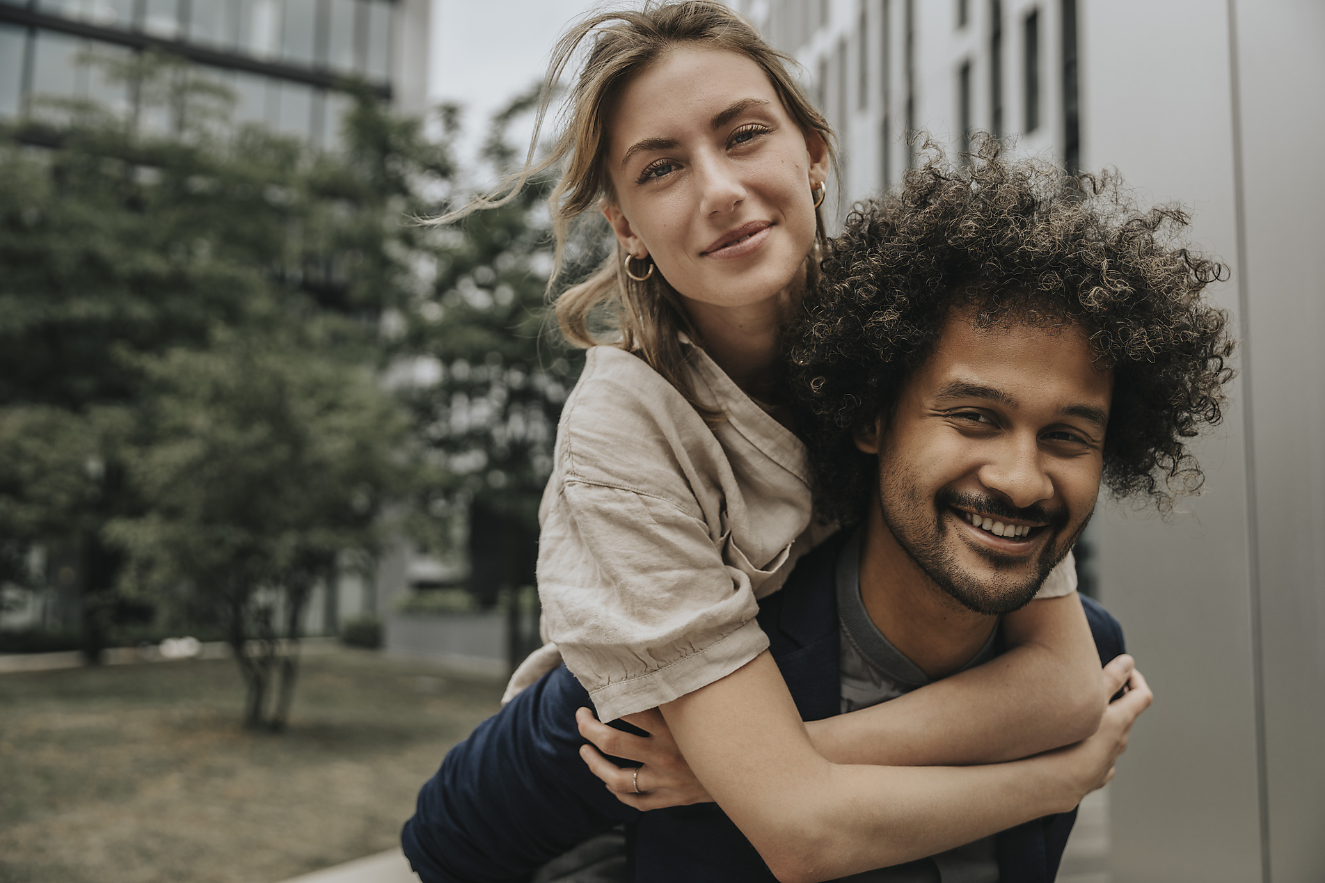 Stock Image, Royalty Free, Smiling boyfriend giving piggyback ride to girlfriend in front of modern building