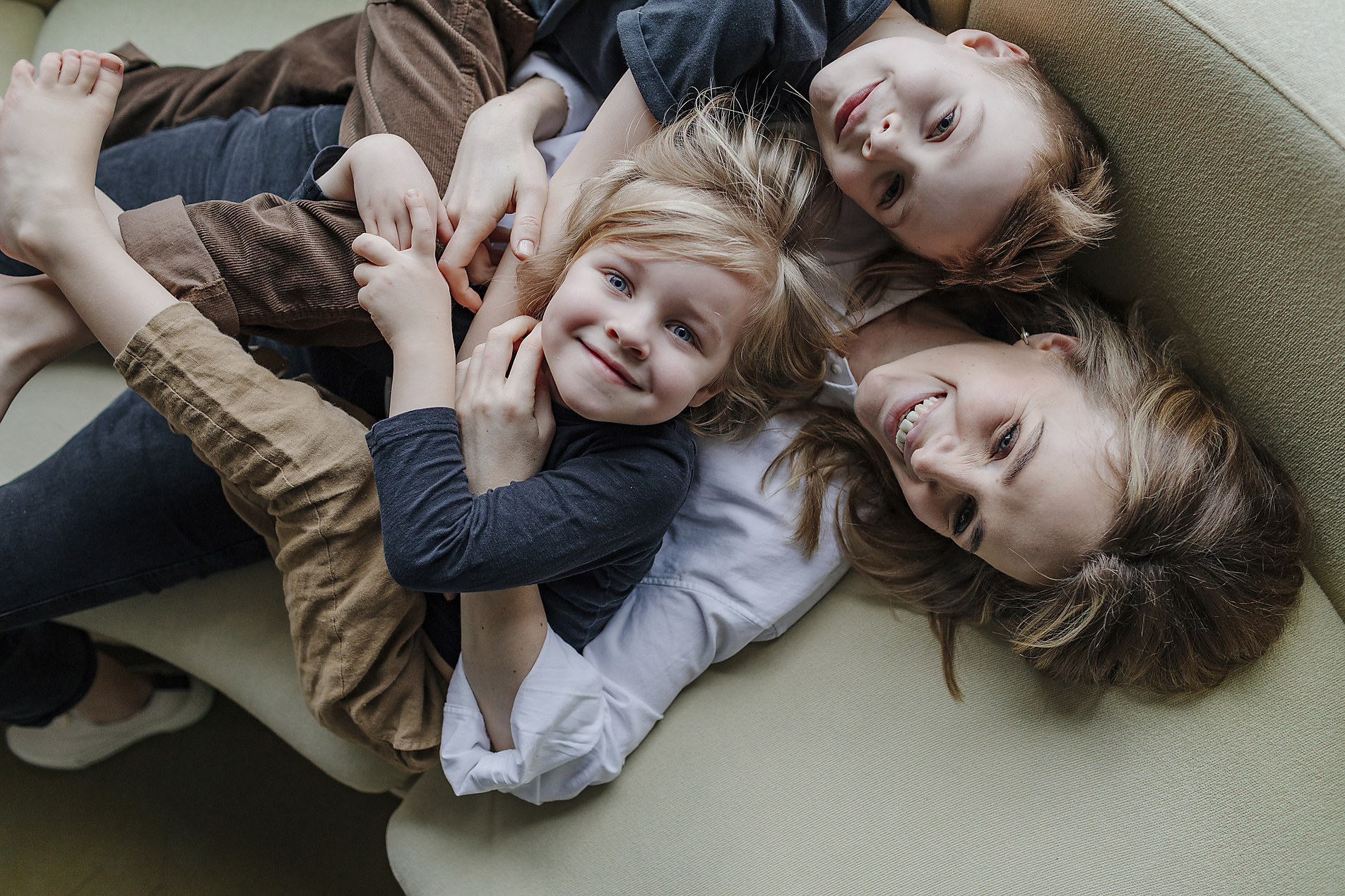 Stock Image, Royalty Free, High angle view of happy mother lying with sons on sofa in living room at home