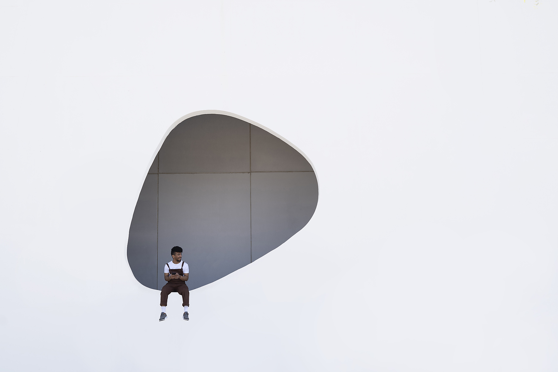 Stockphoto, Royalty Free Stock Image, Young man sitting on wall with hole in building