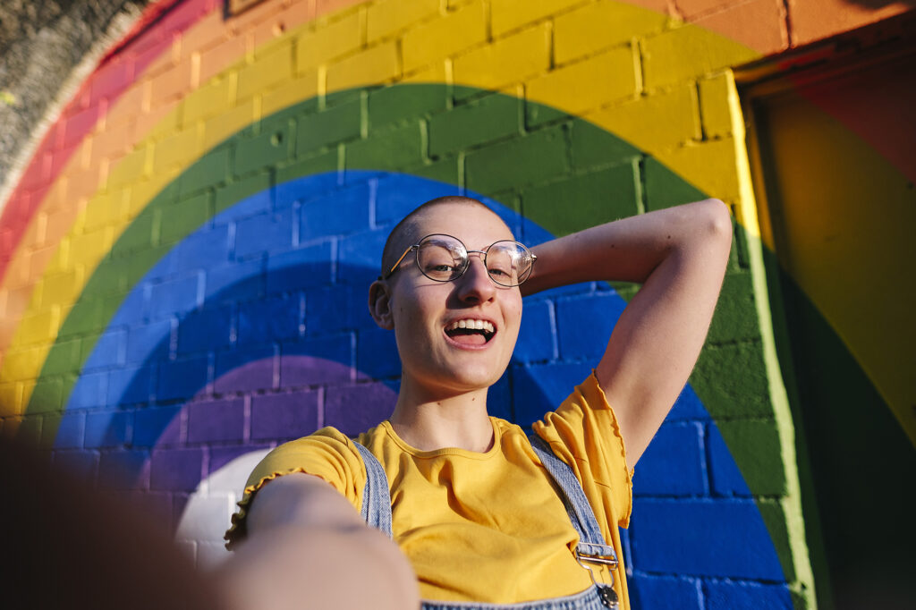 Happy androgynous person with hand behind shaved head taking selfie in front if rainbow wall Royalty free image Happy androgynous person with hand behind shaved head taking selfie in front if rainbow wall
Royalty free image