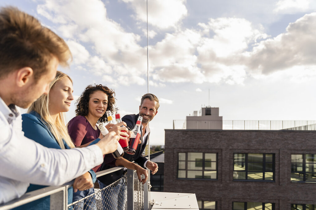 Lächelnde Mitarbeiter stoßen auf der Terrasse mit Flaschen an
Lizenzfreies Stockfoto