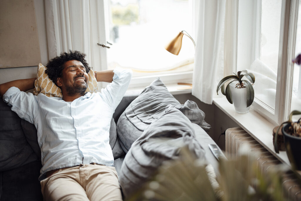 Lächelnder Mann mit geschlossenen Augen, der sich zu Hause auf dem Sofa ausruht
Lizenzfreies Stockfoto