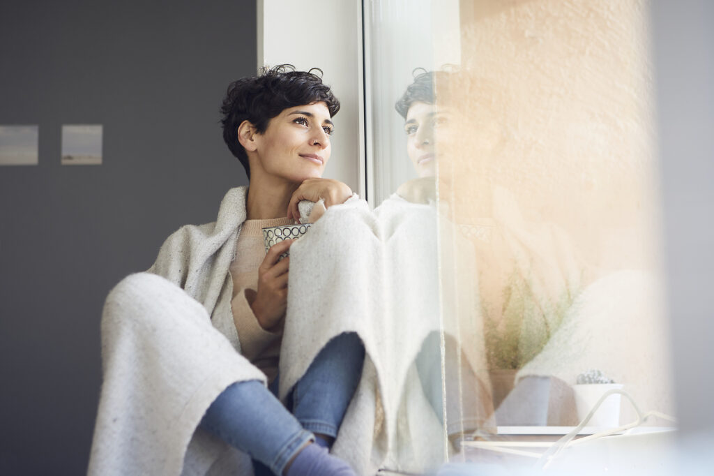 Relaxed woman at home sitting at the window Stockphoto Relaxed woman at home sitting at the window Stockphoto