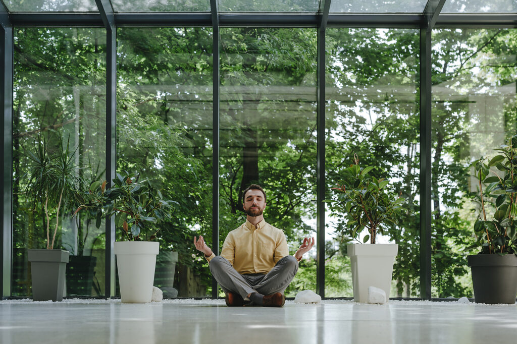 Businessman meditating with eyes closed in front of window Stockphoto Businessman meditating with eyes closed in front of window Stockphoto