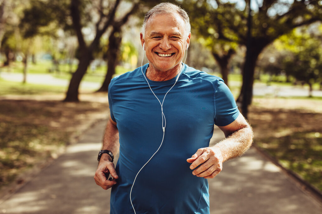 Portrait of a senior man in fitness wear running in a park. Close up of a smiling man running while listening to music using earphones.
Royalty free image