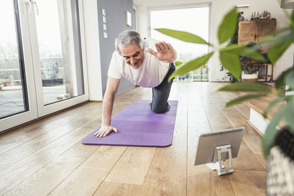 Smiling senior man balancing on exercise mat doing workout at home
Royalty free image