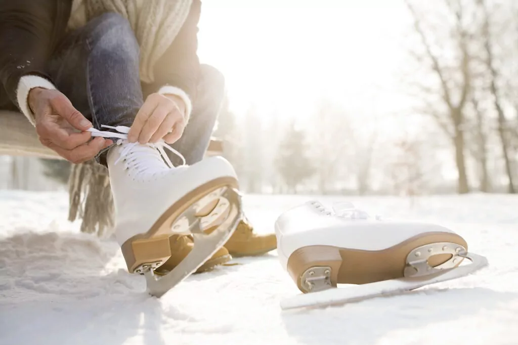 Woman sitting on bench in winter landscape putting on ice skates
Royalty free image