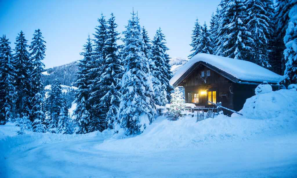 Austria, Altenmarkt-Zauchensee, sledges, snowman and Christmas tree at illuminated wooden house in snow at dusk
Royalty free image