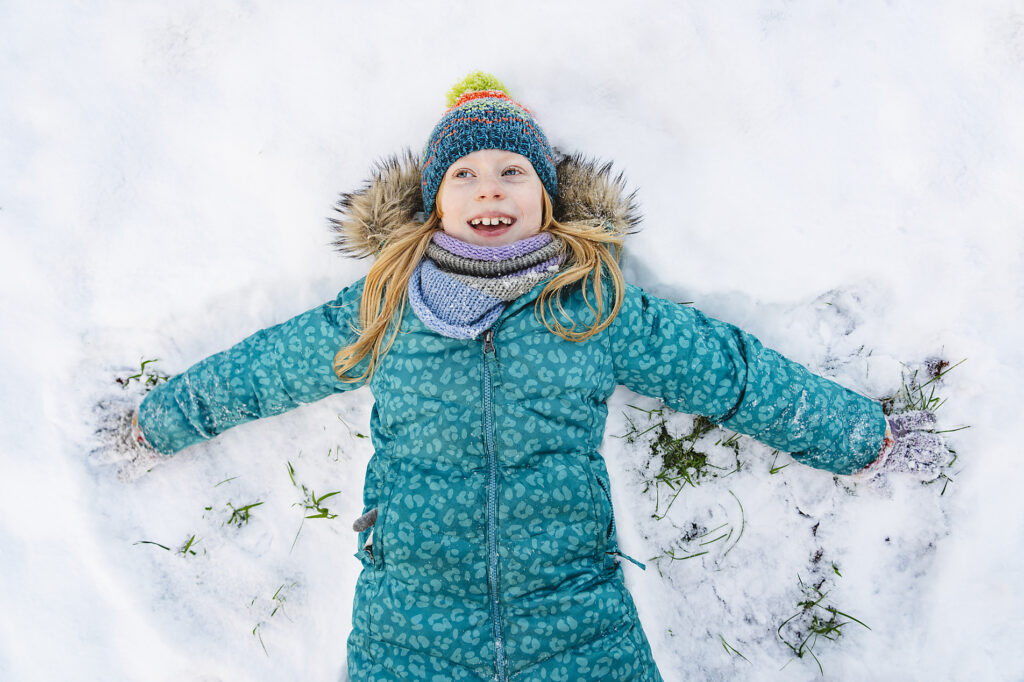 Glückliches Mädchen liegt auf dem Rücken und macht Schneeengel
Lizenzfreies Stockfoto