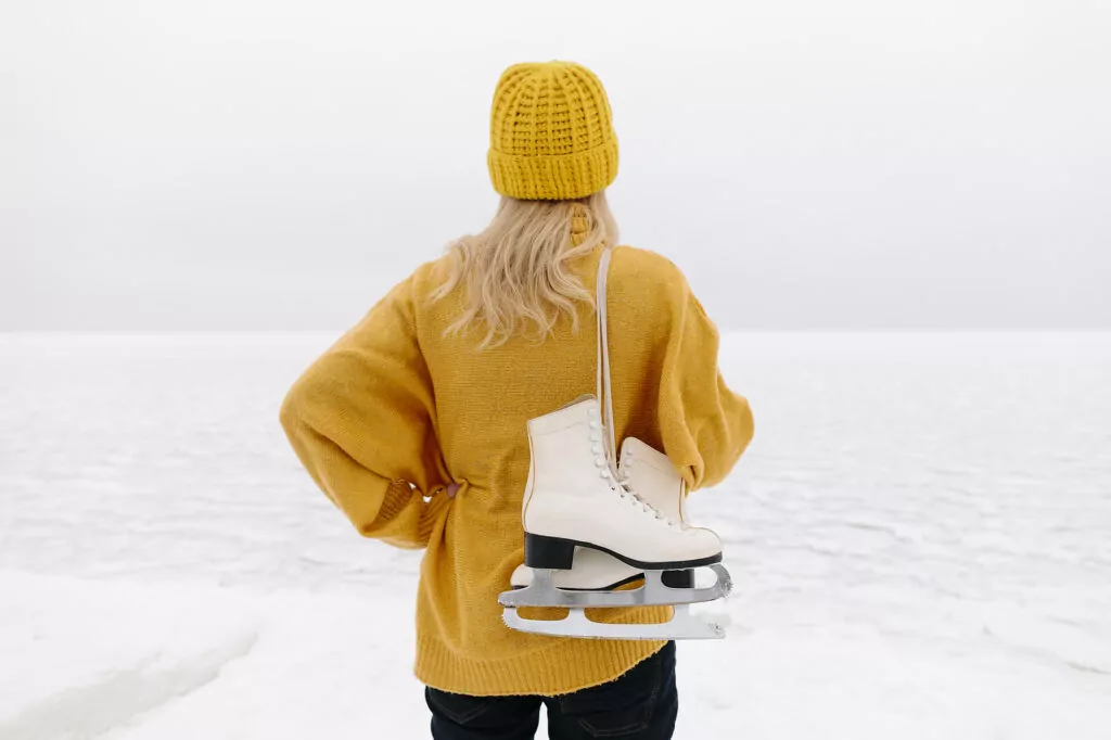 Woman in warm clothing standing with ice skates in front of winter sea
Royalty free image