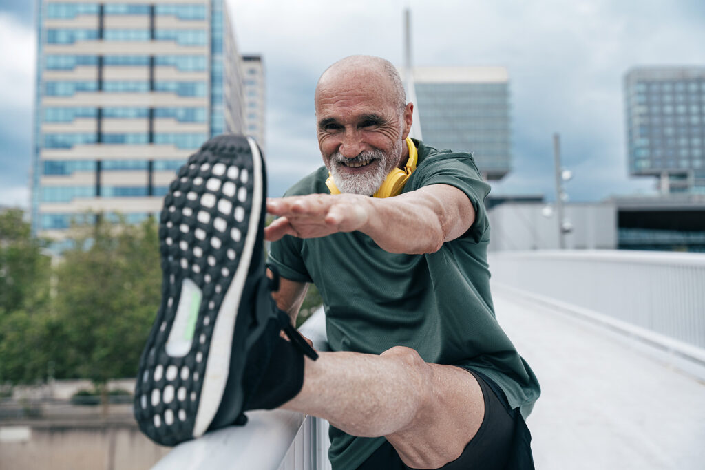 Smiling senior man stretching leg on railing at footbridge in city Royalty free image Smiling senior man stretching leg on railing at footbridge in city
Royalty free image