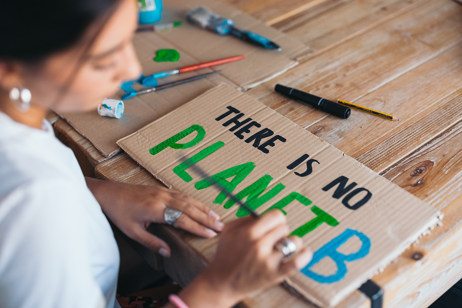 A cheerful young woman paints an text design on cardboard, surrounded by painting supplies in a cozy room, highlighting environmental consciousness.
Royalty free image
