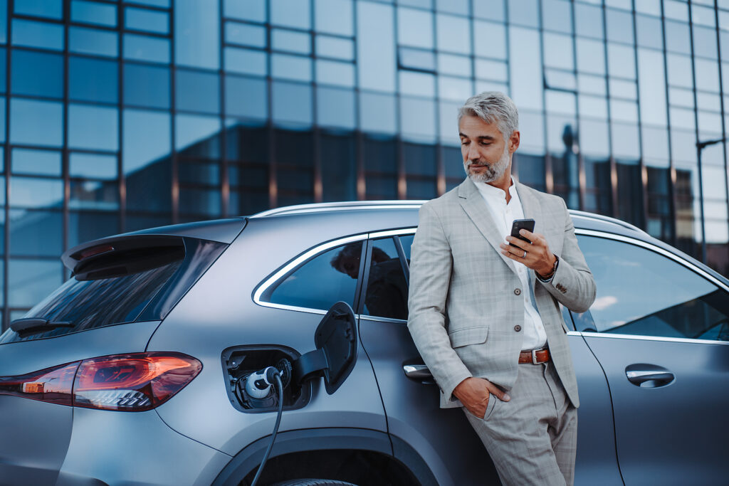 Ein Geschäftsmann hält sein Smartphone in der Hand, während er sein Auto an einer Ladestation für Elektrofahrzeuge auflädt, Nahaufnahme. Lizenzfreies Stockfoto Ein Geschäftsmann hält sein Smartphone in der Hand, während er sein Auto an einer Ladestation für Elektrofahrzeuge auflädt, Nahaufnahme.
Lizenzfreies Stockfoto