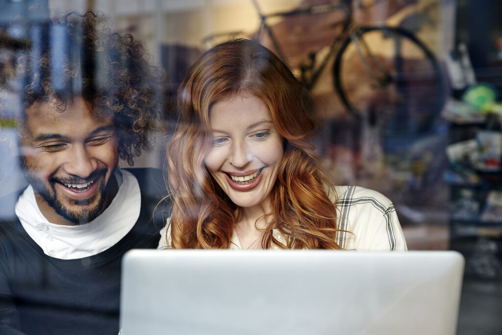 Happy young couple using laptop behind windowpane
Royalty-free image