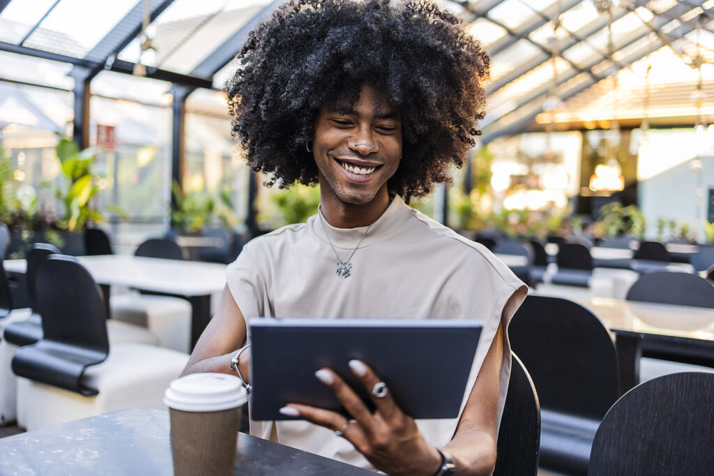 Smiling young man with curly hair using tablet PC at cafe
Royalty-free image