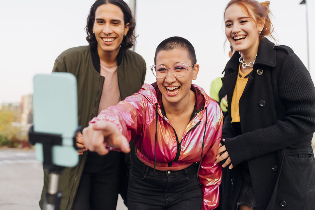 Happy woman pointing at phone with friends on footpath
Royalty-free image