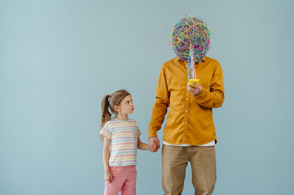 Daughter looking at father with mask of chaotic thoughts using smart phone Royalty-free image Daughter looking at father with mask of chaotic thoughts using smart phoneRoyalty-free image