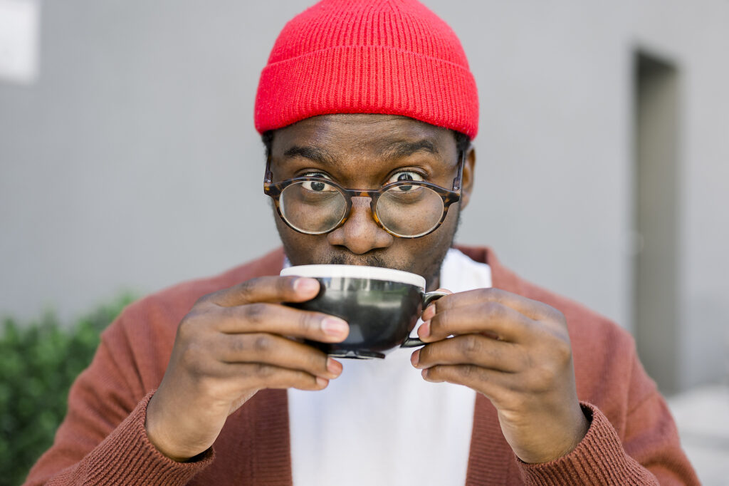 Smiling man in eyeglasses and red beanie enjoying coffee outdoors Royalty-free image Smiling man in eyeglasses and red beanie enjoying coffee outdoors
Royalty-free image