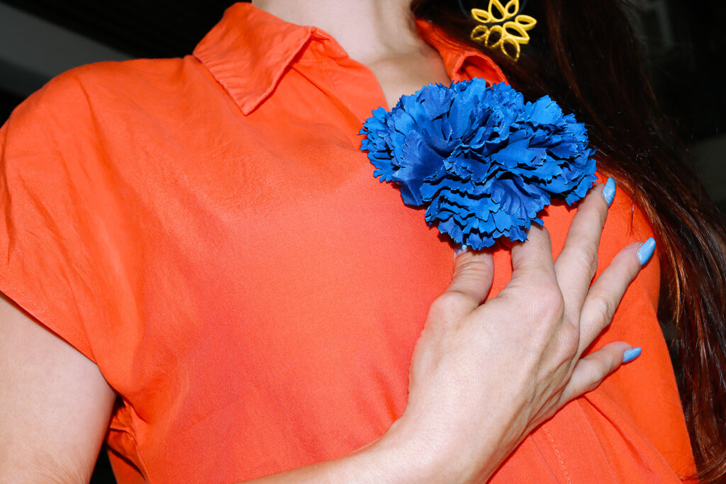 Hand touching blue carnation on orange shirt at Feria de Abril
Royalty-free image