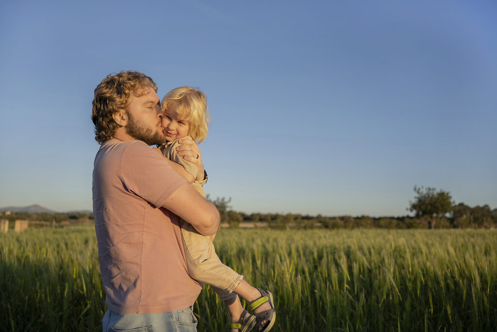 Happy father holding and kissing kid in summer field at sunset
Royalty-free image