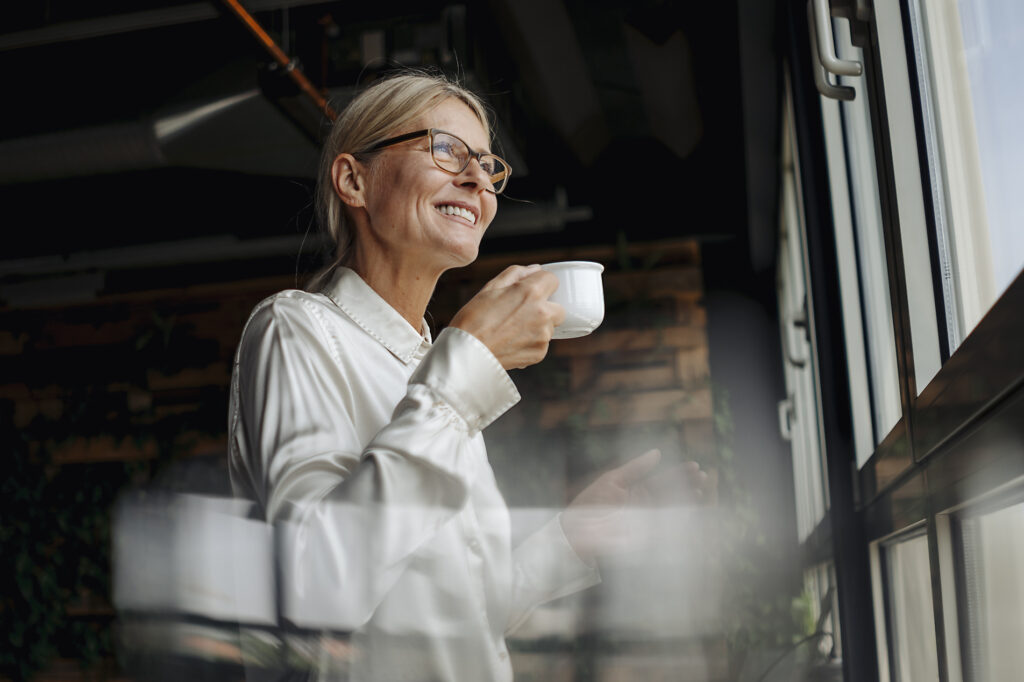 Smiling businesswomanholding cup of coffee looking out of window
Royalty-free image