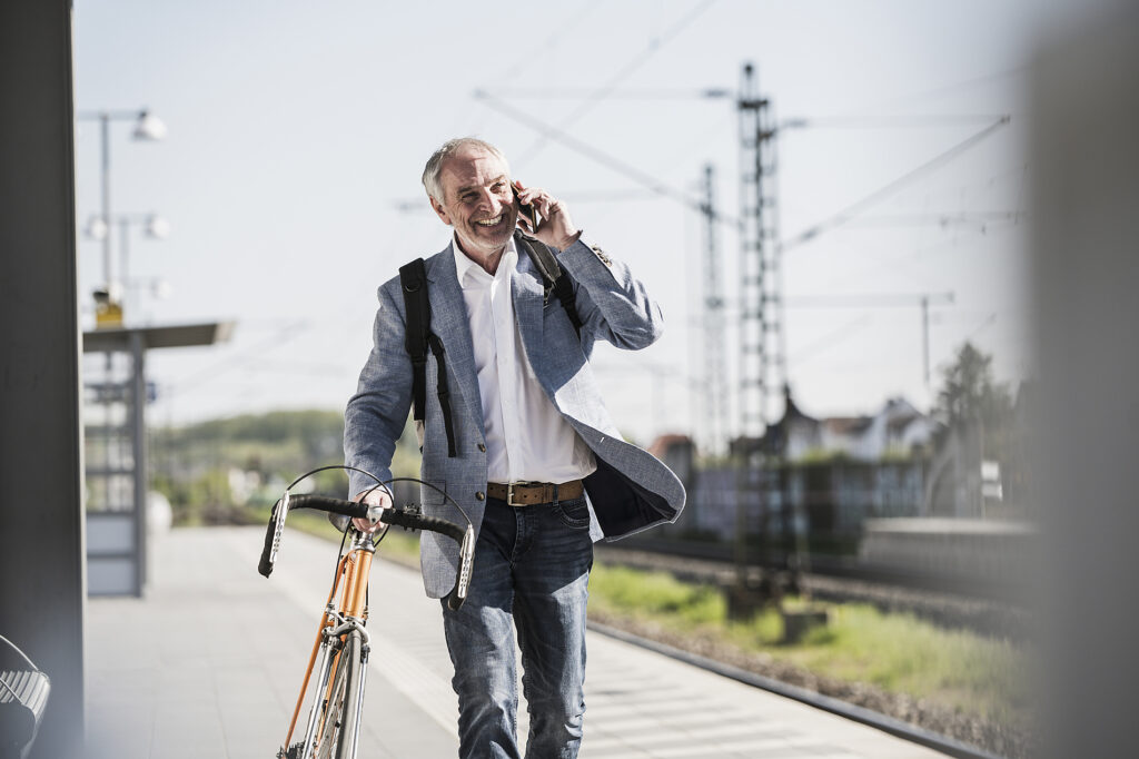 Glücklicher Geschäftsmann, der mit dem Handy telefoniert und mit dem Fahrrad am Bahnsteig spazieren geht Lizenzfreies Stockfoto Glücklicher Geschäftsmann, der mit dem Handy telefoniert und mit dem Fahrrad am Bahnsteig spazieren geht
Lizenzfreies Stockfoto
