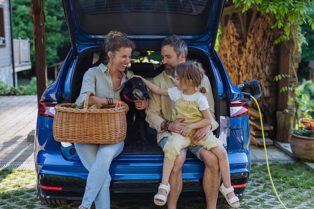 Happy family sitting in a car trunk and waiting for charging, preparations for picnic. Royalty-free image Happy family sitting in a car trunk and waiting for charging, preparations for picnic.
Royalty-free image