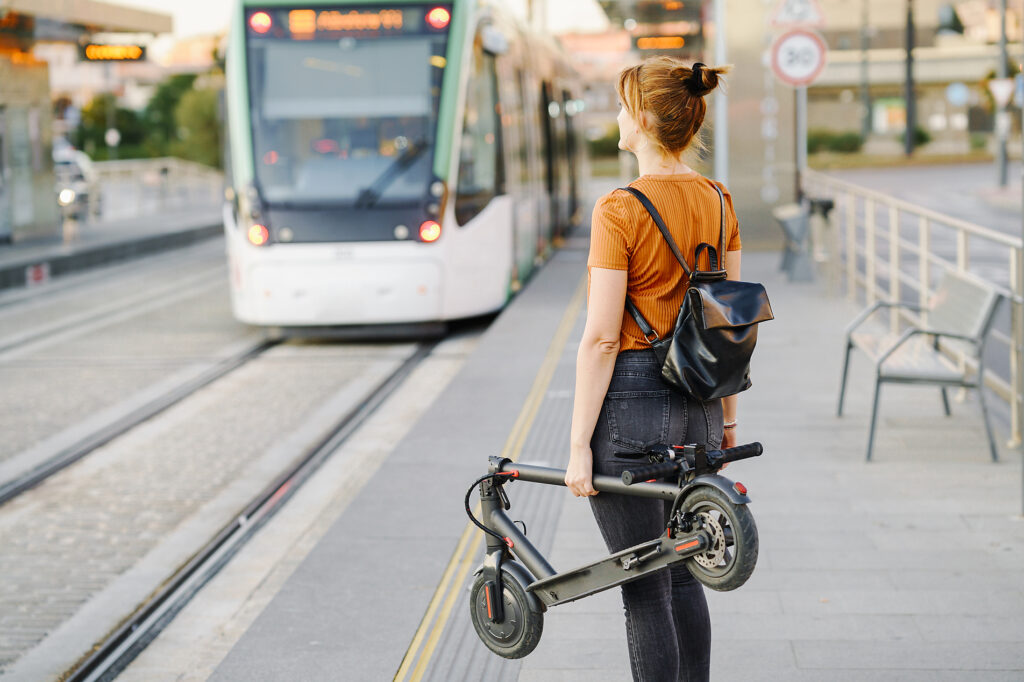 Back view of woman with backpack and folded electric scooter waiting at tram stop Royalty-free image Back view of woman with backpack and folded electric scooter waiting at tram stop
Royalty-free image
