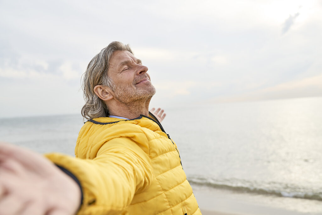 Smiling senior man with arms outstretched standing at beach Royalty-free image Smiling senior man with arms outstretched standing at beach
Royalty-free image