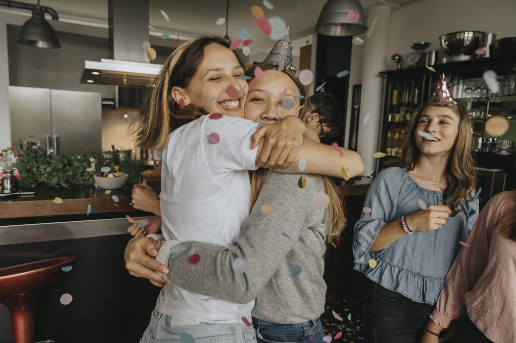 Glückliche Freunde, die sich umarmen, während sie inmitten von Konfetti auf einer Geburtstagsparty zu Hause stehen Lizenzfreies Stockfoto Glückliche Freunde, die sich umarmen, während sie inmitten von Konfetti auf einer Geburtstagsparty zu Hause stehen
Lizenzfreies Stockfoto