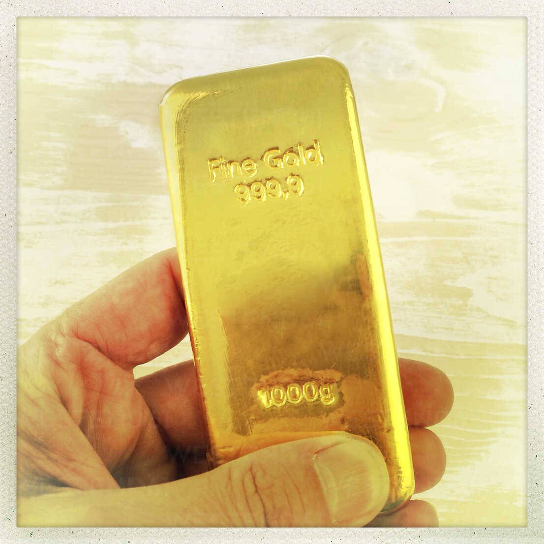 Male hand with 1 kg gold bar stock photo
