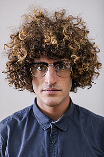 Portrait of serious looking man with curly hair wearing glasses stock photo