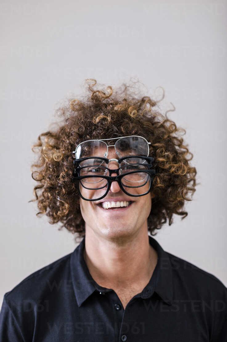 Portrait of smiling man with curly hair wearing four different glasses  stock photo