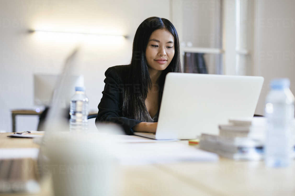 Young Asian woman working in office using laptop stock photo