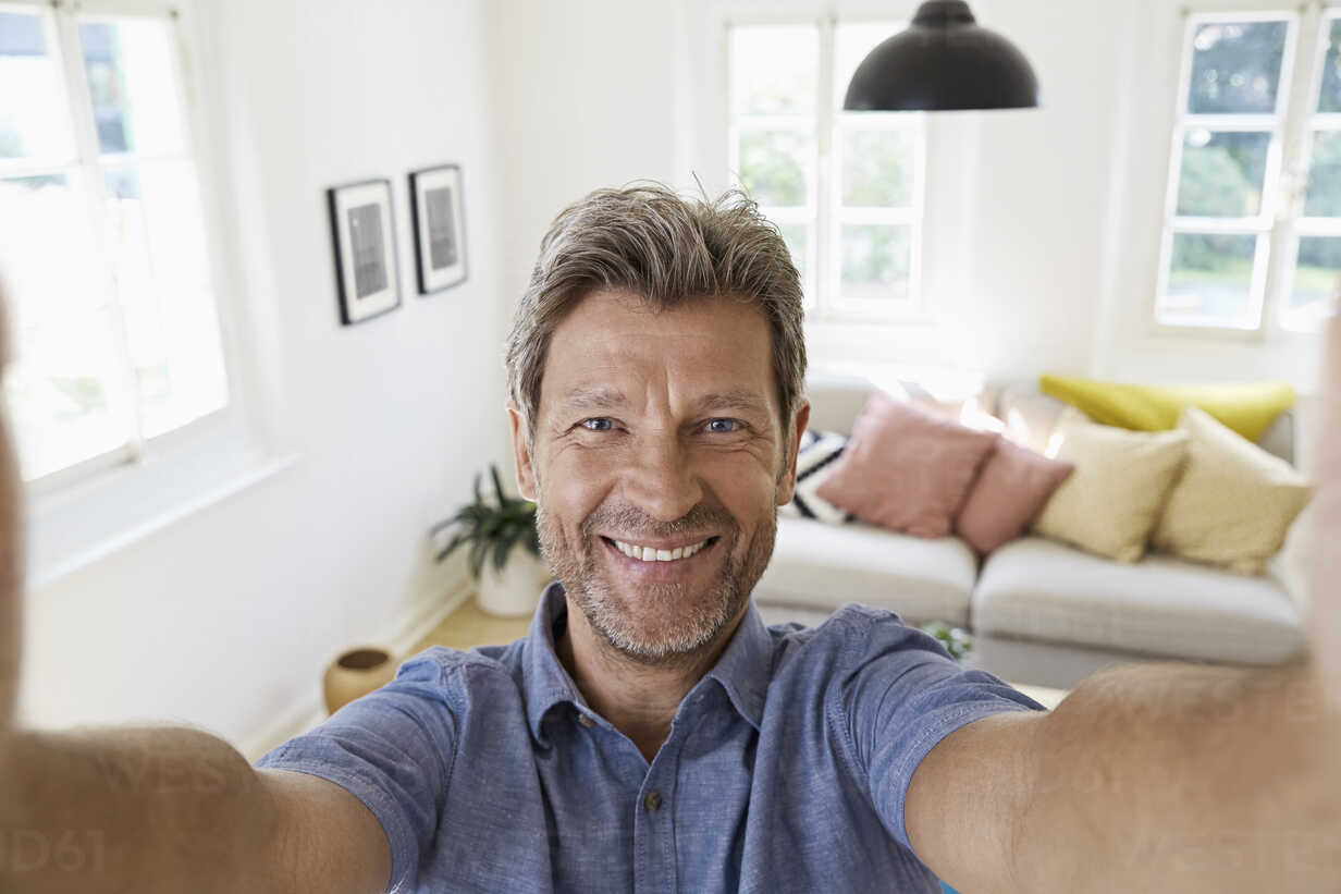 Mature man at home taking a selfie stock photo. 