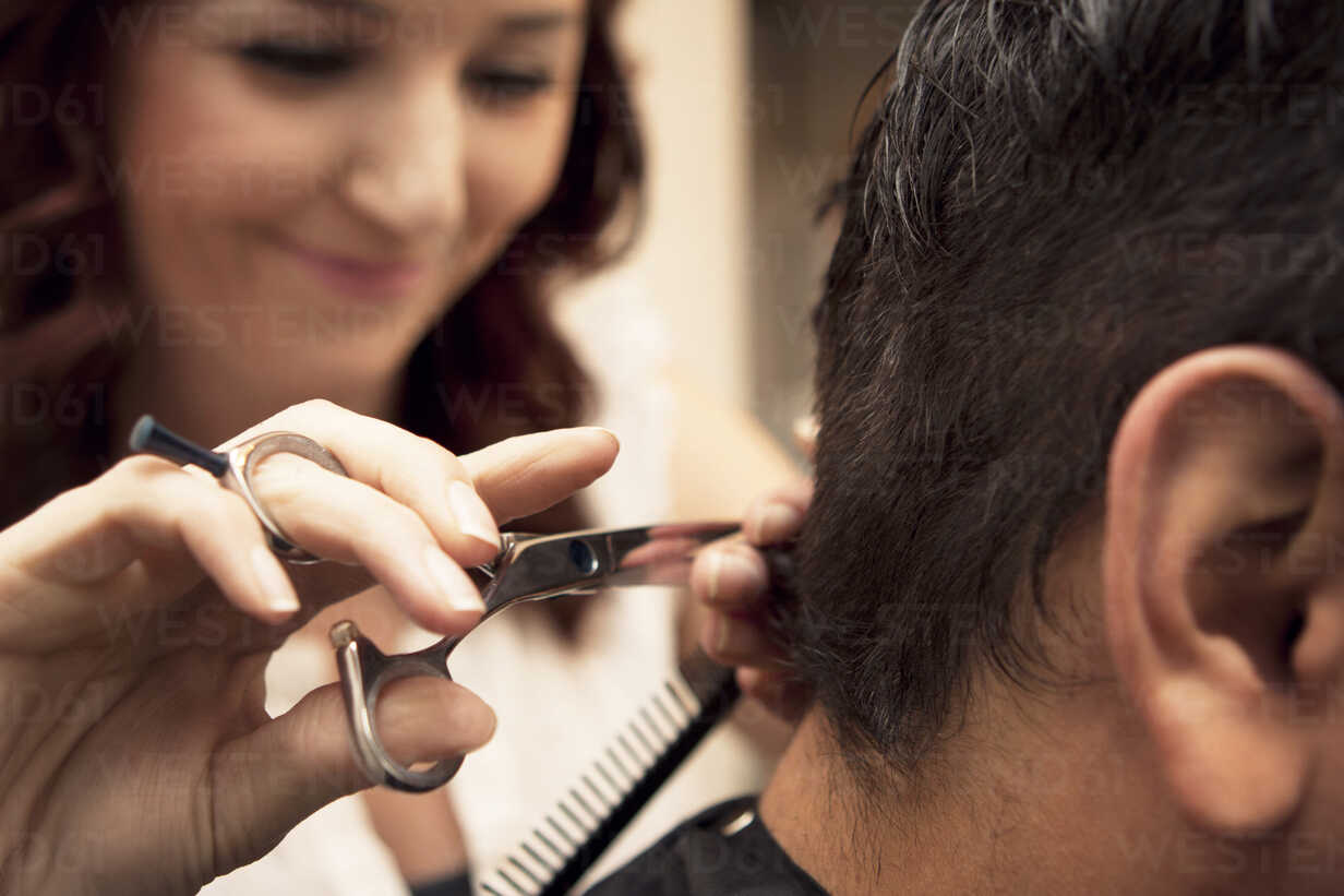 Close-up of female barber cutting hair of male customer in salon stock photo
