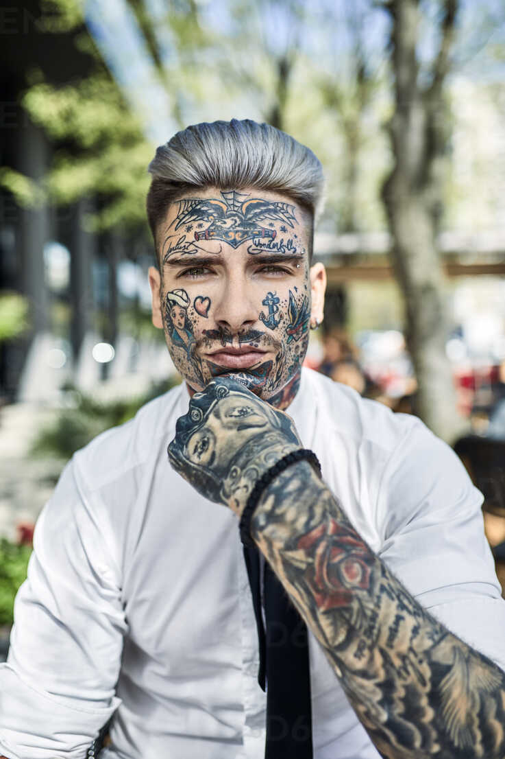 Young businessman with tattooed face, looking at camera stock photo