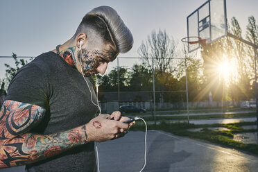 Portrait of tattooed young man with basketball on court stock photo