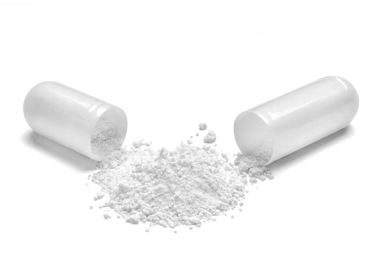 Opened white capsule and white powder on white background stock photo